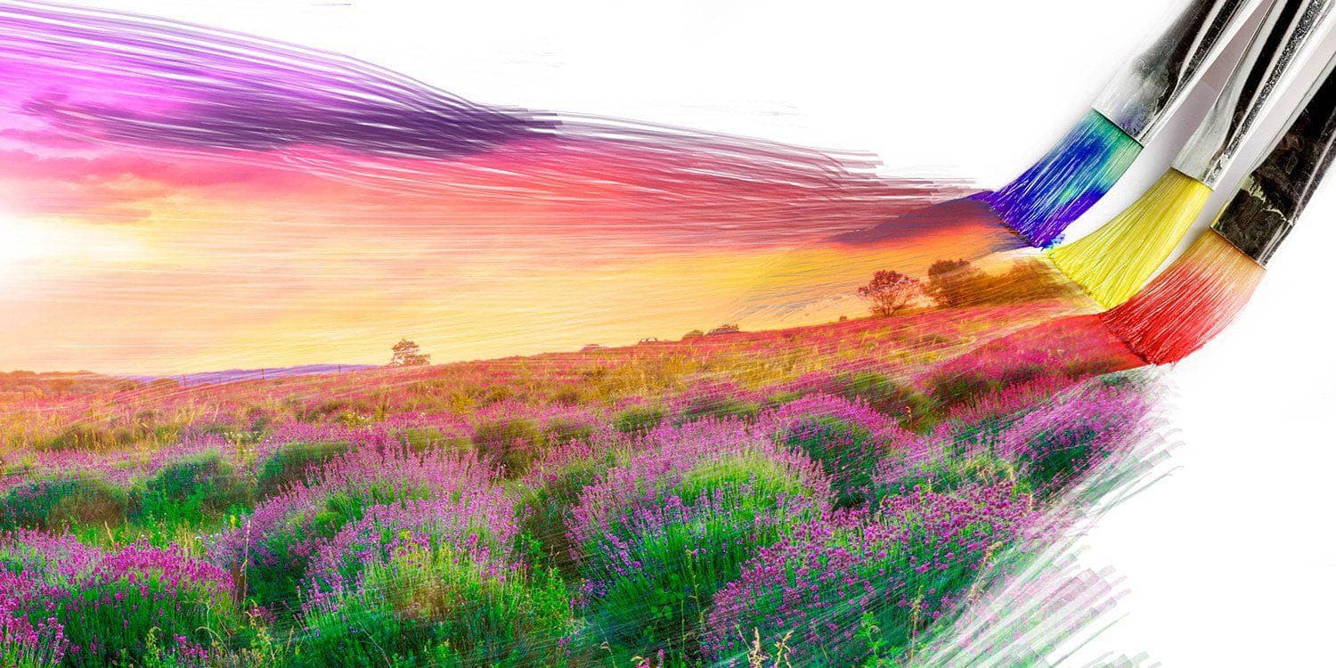 A wide artwork where vivid brushstrokes sweep across a luminous field and horizon, with paintbrushes visible at the right edge.